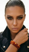 Load image into Gallery viewer, Woman wearing a dark jacket and a Sasha L Jewels Orange beaded bracelet on a white background