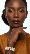 Load image into Gallery viewer, Woman with dark skin and red lipstick wearing a mustard yellow top, Sasha L Jewels Designer white bracelet bangles.